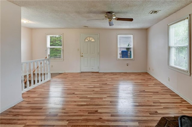 interior space with light wood-style floors, ceiling fan, a textured ceiling, and visible vents