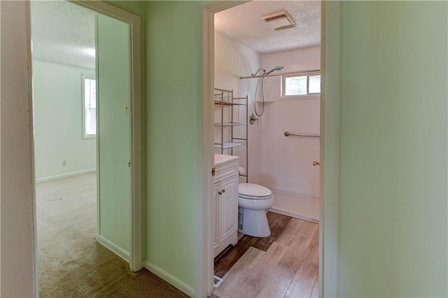 full bathroom with a textured ceiling, visible vents, vanity, baseboards, and toilet