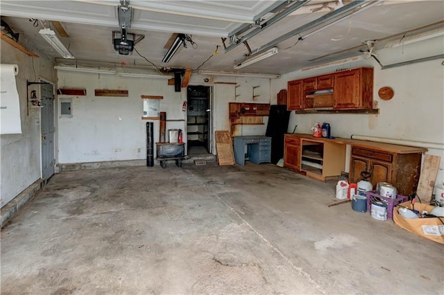 garage with a workshop area, a garage door opener, and electric panel