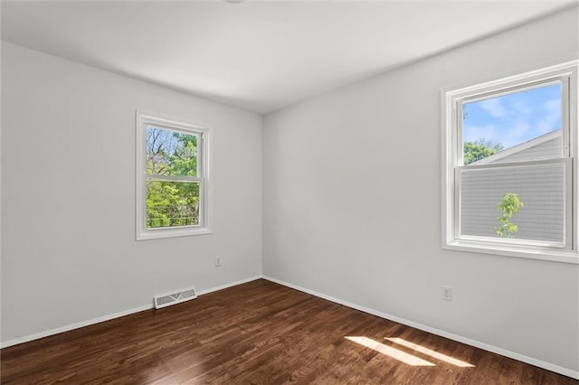 unfurnished room with baseboards and dark wood-type flooring