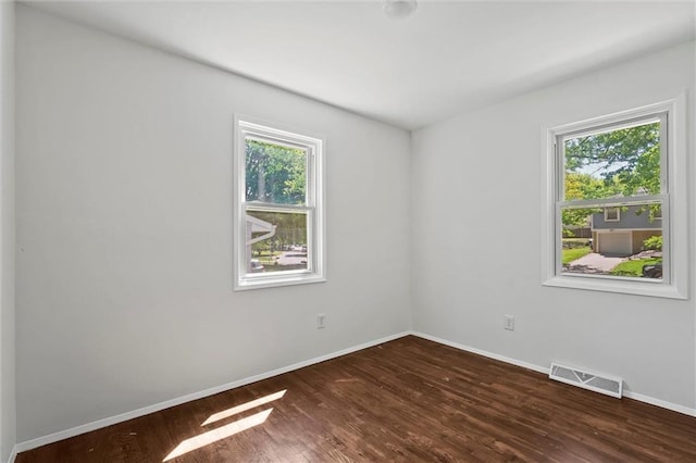 empty room with healthy amount of natural light, baseboards, and dark wood-style floors