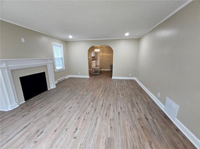 unfurnished living room with visible vents, ornamental molding, wood finished floors, recessed lighting, and arched walkways