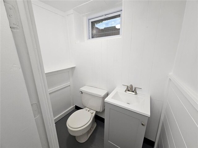 bathroom featuring vanity, a decorative wall, and toilet