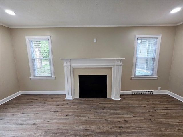 unfurnished living room featuring crown molding, recessed lighting, baseboards, wood finished floors, and visible vents