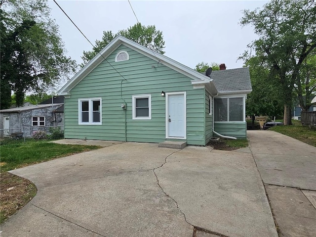 rear view of property featuring a patio, fence, and a chimney