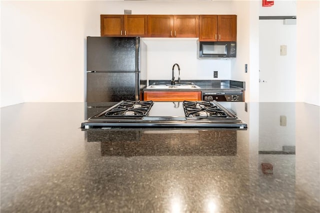 kitchen with brown cabinetry, a sink, and black appliances