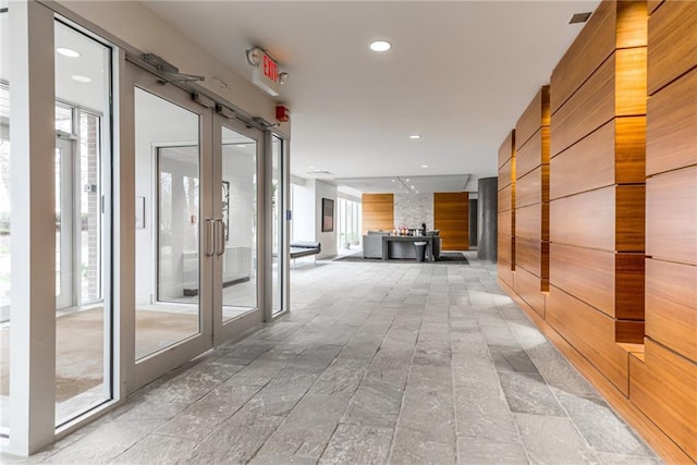 corridor featuring recessed lighting, stone finish floor, and french doors