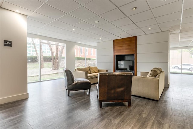 living area featuring a paneled ceiling, dark wood-style floors, and a wealth of natural light