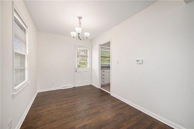 3525-3527 Bell St, Kansas City, MO 64111 - unfurnished dining area with visible vents, baseboards, dark wood-type flooring, and a notable chandelier