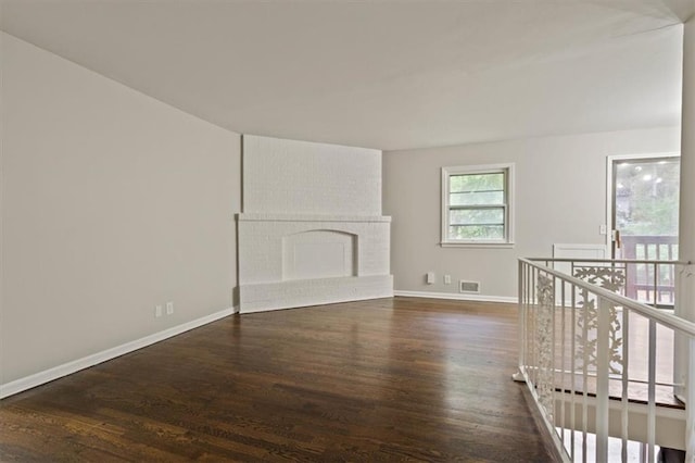 unfurnished living room with baseboards, visible vents, wood finished floors, and a fireplace