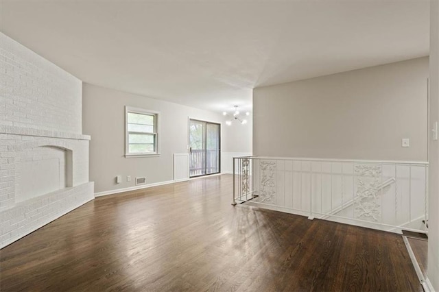 unfurnished living room with a chandelier, visible vents, wood finished floors, and a fireplace