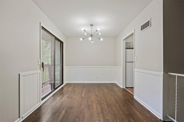 unfurnished dining area with a notable chandelier, wood finished floors, visible vents, and a wainscoted wall