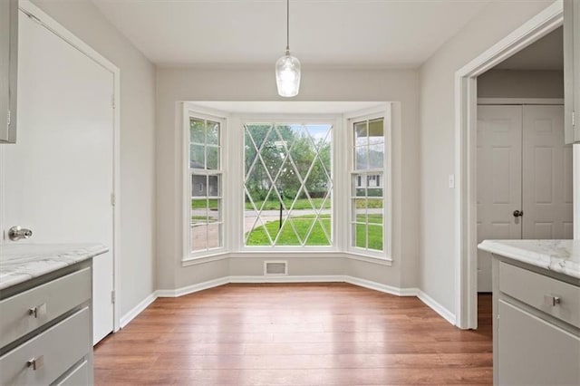 unfurnished dining area with baseboards, light wood-style flooring, and visible vents