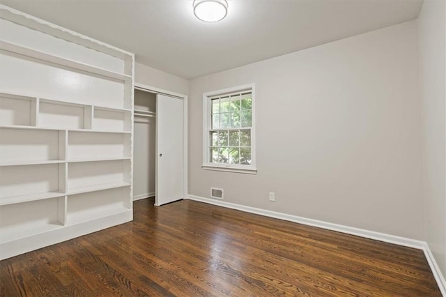 unfurnished bedroom with visible vents, baseboards, dark wood-style flooring, and a closet