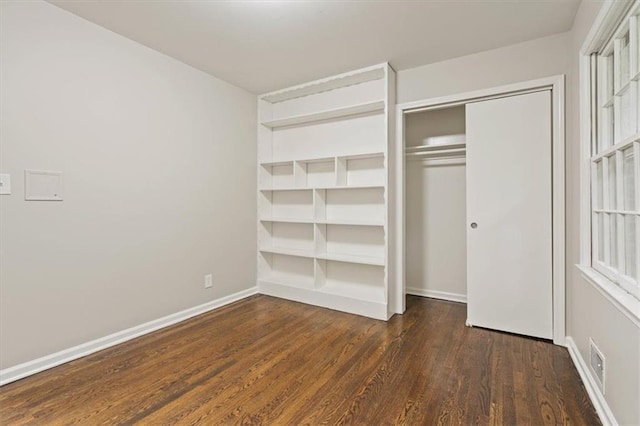 unfurnished bedroom featuring visible vents, baseboards, wood finished floors, and a closet