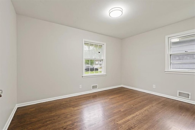 empty room featuring baseboards, wood finished floors, and visible vents