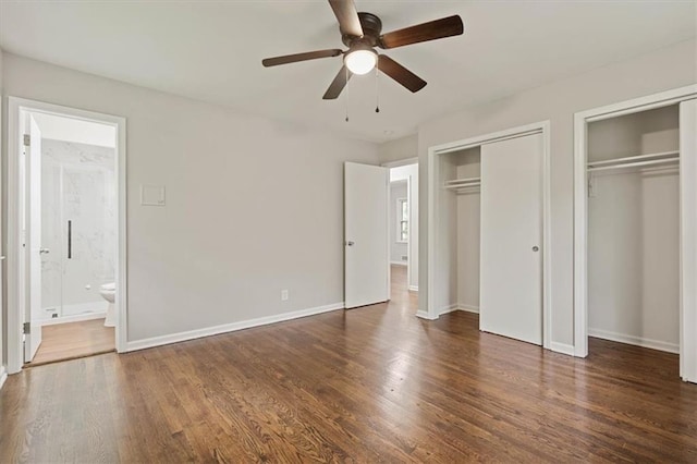 unfurnished bedroom featuring baseboards, multiple closets, wood finished floors, and ensuite bath