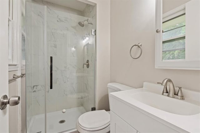 bathroom featuring toilet, a marble finish shower, and vanity