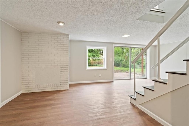 interior space featuring stairs, a textured ceiling, baseboards, and wood finished floors