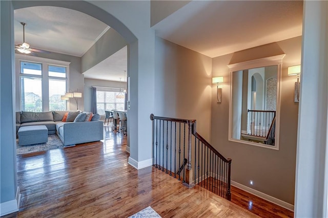 corridor with baseboards, wood finished floors, and an upstairs landing