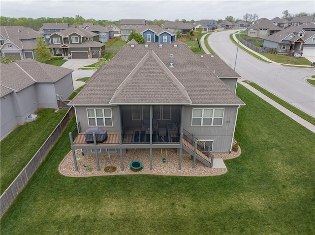 back of house featuring a yard, roof with shingles, a residential view, and a sunroom