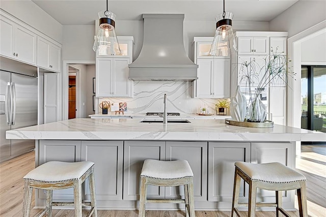 12605 W 170th St, Overland Park, KS 66221 - kitchen with wall chimney range hood, built in refrigerator, decorative backsplash, white cabinets, and light stone counters