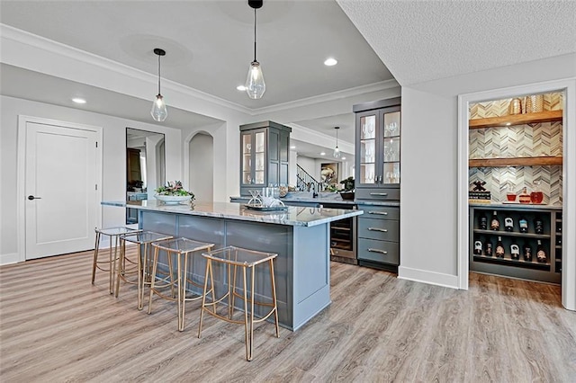 12605 W 170th St, Overland Park, KS 66221 - kitchen with a breakfast bar, gray cabinets, light wood finished floors, wine cooler, and glass insert cabinets