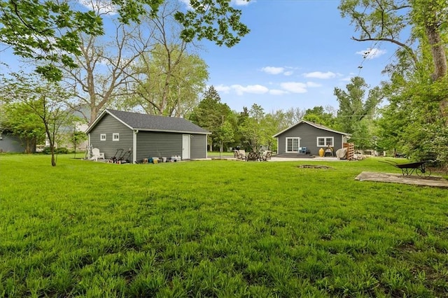 view of yard featuring an outbuilding, a patio area, and an outdoor fire pit
