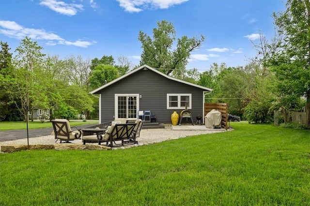 rear view of property with a patio, a yard, and a fire pit