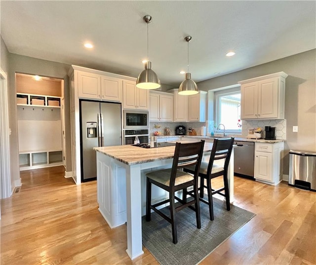 kitchen with white cabinets, stainless steel appliances, a kitchen island, and a sink