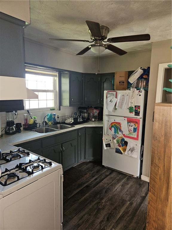 8212 NE 51st St, Kansas City, MO 64119 - kitchen with white appliances, extractor fan, dark wood-type flooring, light countertops, and a sink