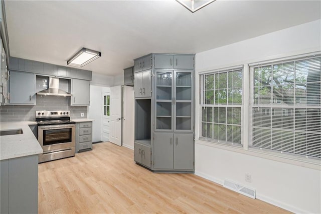 321 22nd Street Ter, Blue Springs, MO 64015 - kitchen with visible vents, wall chimney exhaust hood, electric stove, light wood-style flooring, and gray cabinetry