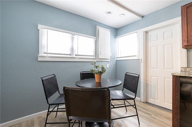 dining room with baseboards, a textured wall, and light wood finished floors