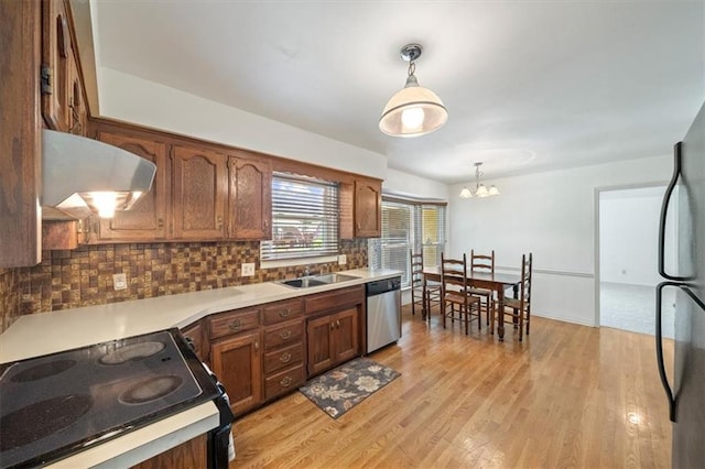 4071 SW Royale Ct, Lees Summit, MO 64082 - kitchen featuring stainless steel appliances, backsplash, light wood-style flooring, range hood, and decorative light fixtures