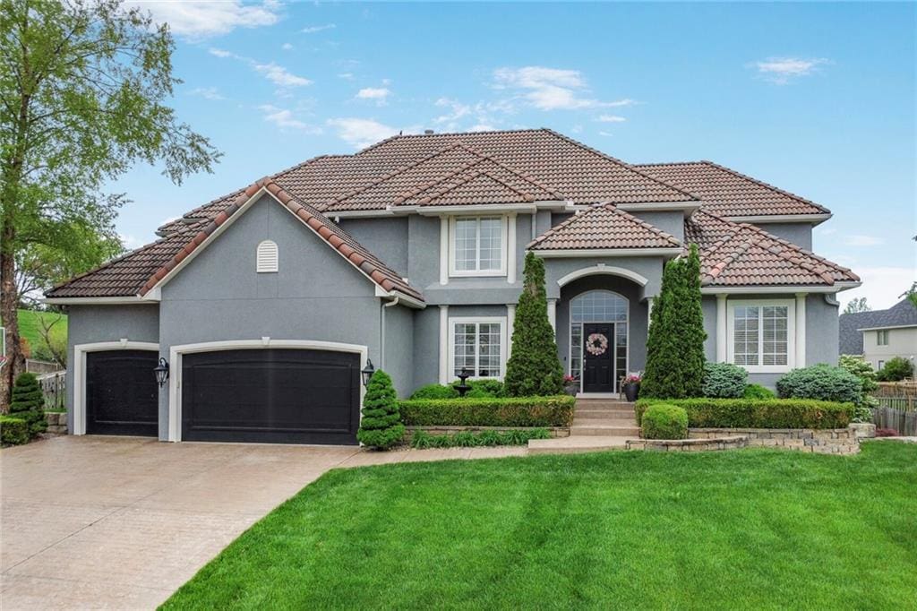 view of front of home with a garage, a front lawn, stucco siding, driveway, and a tile roof