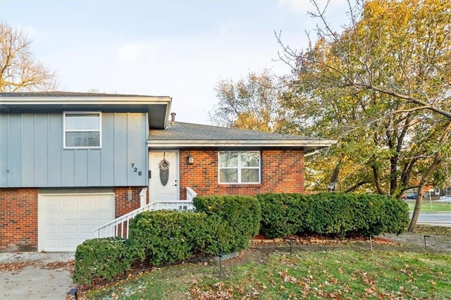 tri-level home with board and batten siding, brick siding, concrete driveway, and a garage