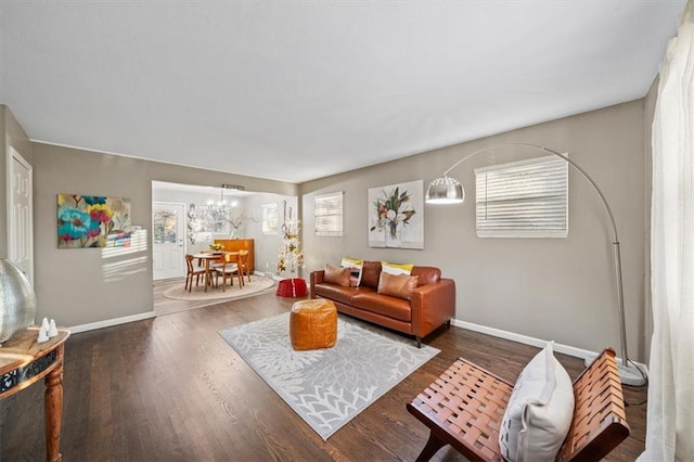 living area featuring baseboards, wood finished floors, and a notable chandelier
