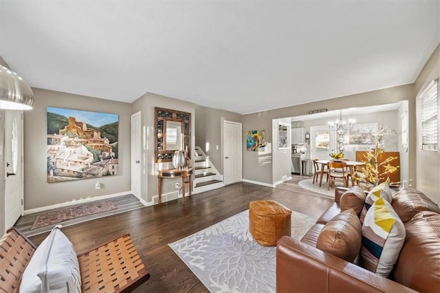 living area with an inviting chandelier, baseboards, stairway, and wood finished floors