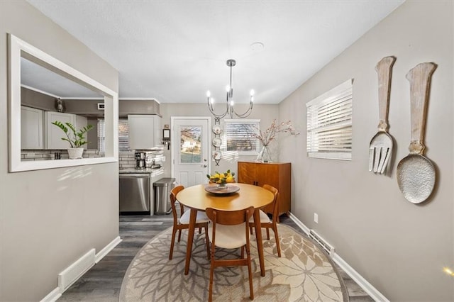dining room featuring baseboards, visible vents, dark wood-style floors, and a chandelier