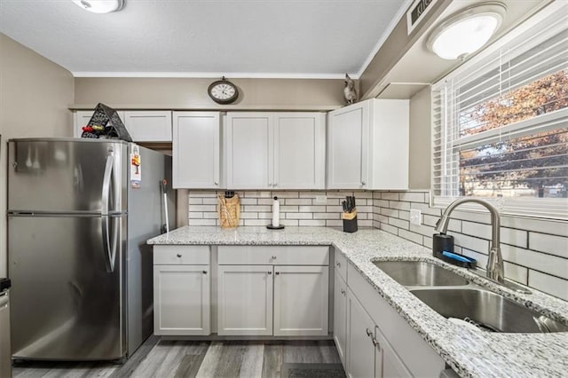 kitchen featuring a sink, tasteful backsplash, freestanding refrigerator, and wood finished floors