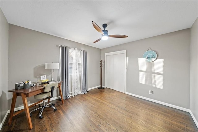 home office with a ceiling fan, baseboards, and wood finished floors