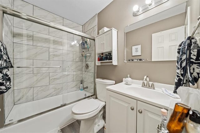 full bath with toilet, bath / shower combo with glass door, and vanity