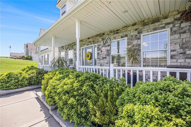 property entrance with covered porch and stone siding
