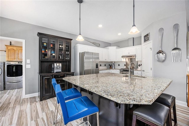 kitchen with visible vents, high end appliances, a sink, baseboards, and white cabinetry