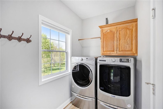 washroom with baseboards, cabinet space, and washing machine and dryer