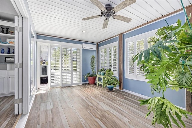 sunroom / solarium featuring baseboards, a wall unit AC, wood ceiling, and wood finished floors