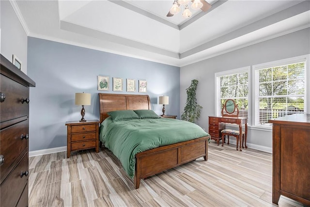 bedroom with baseboards, multiple windows, ornamental molding, and a tray ceiling