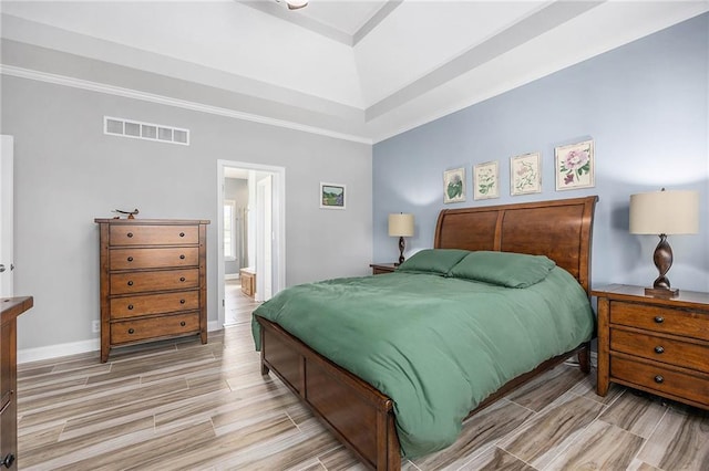 bedroom with visible vents, baseboards, light wood-style floors, ornamental molding, and a tray ceiling
