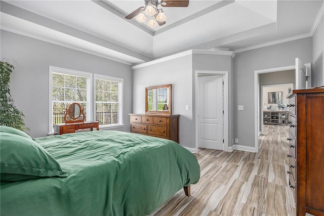 bedroom featuring light wood-style floors, ornamental molding, baseboards, and a raised ceiling