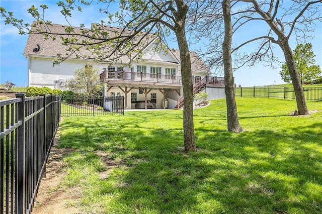 rear view of property with a fenced backyard, a wooden deck, a yard, and stairway